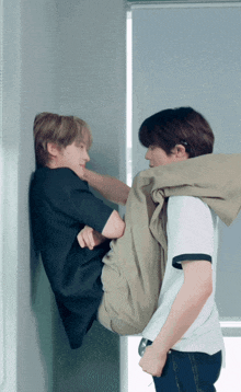 a man is carrying another man up against a wall with a blanket