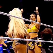 a couple of women are standing in a wrestling ring giving each other high fives .