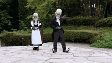 a man in a tuxedo and a woman in a maid outfit are standing next to each other