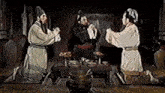 three men are kneeling in front of a table with a bucket on it