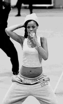 a black and white photo of a woman wearing a beanie and a crop top .