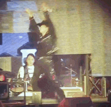 a man in a black jacket is dancing on a stage