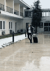 a man is walking down a sidewalk with a suitcase in front of a building that says bjk istanbul