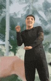 a man in a black shirt and black pants is dancing in front of a palm tree