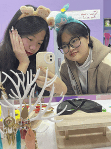 two girls are taking a picture of themselves in front of a mirror with a sign that says " drive safe " on it