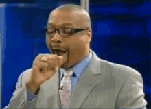 a man in a suit and tie is making a funny face while wearing glasses .