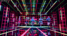 a group of girls are dancing in a neon room with honeycam.org written on the bottom