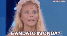 a woman with blonde hair and blue eyes is wearing a flower crown and says eandato in onda ?