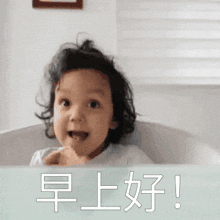 a little girl is sitting in a bathtub with chinese writing on the bottom
