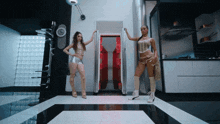 two women are standing in a room with a red door