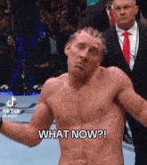 a shirtless man is standing in a boxing ring and says " what now "
