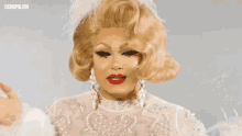 a woman with blonde hair and red lips is wearing feathers
