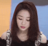 a close up of a woman 's face with her eyes closed . she is wearing a black top and a necklace .