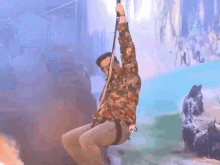 a man is hanging upside down on a rope while wearing a camouflage shirt