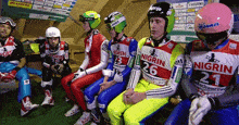 a group of skiers are sitting in a locker room and one of them is wearing a nigrin shirt