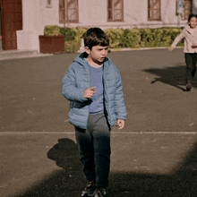 a boy in a blue jacket is walking on a street