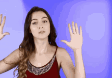 a woman in a red tank top waves her hand