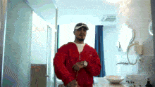 a man in a red jacket stands in a bathroom with a sink