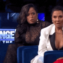 two women are sitting in front of a sign that says nge at the bottom