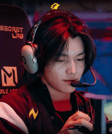 a young man is wearing headphones and a microphone while playing a video game .