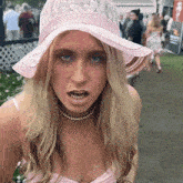 a woman wearing a pink hat and a pearl necklace is making a funny face