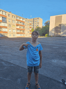 a boy wearing a blue shirt with a cat on it points to his chest
