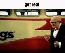 a man in a tuxedo and bow tie is standing in front of a bus that says gs on it .