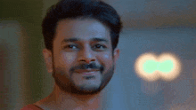 a man with a beard is smiling with a green light in the background .