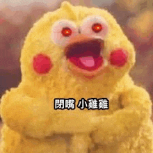 a stuffed yellow chicken with red eyes is making a funny face with its mouth open .