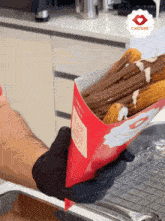 a person is holding a box of churros with chocolate sauce
