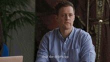 a man in a blue shirt is sitting in front of a laptop and says " shut the @ s # % up "