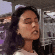 a woman with her eyes closed is smoking a cigarette .