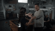 a man and woman are dancing in a room with a foosball table