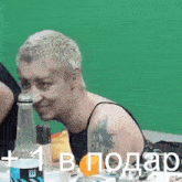 a man with a tattoo on his arm is sitting at a table with a bottle of soda .