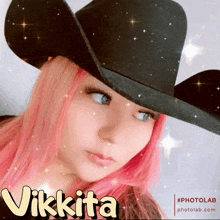 a woman with pink hair wearing a black cowboy hat with the name vikkita written on it