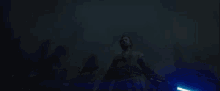 a man is holding a blue lightsaber in his hand in the dark