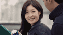 a woman is smiling while holding a can of soda and looking at a man