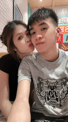 a man wearing a kenzo shirt is kissing a woman