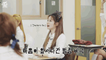 a girl with a bow in her hair is sitting at a desk in a classroom with a twice logo in the corner