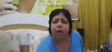 a woman in a blue shirt is looking at the camera