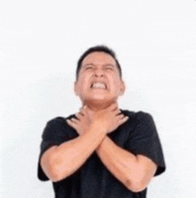 a man in a black shirt is holding his throat .
