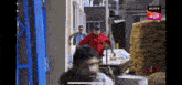 a man in a red shirt is pushing a wheelbarrow in a scene from a sony television show