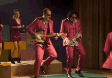 a man in a pink suit is playing a guitar in front of a group of women