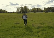 a person running through a grassy field with a house in the background