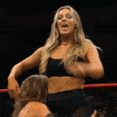 a woman in a black crop top is standing next to another woman in a ring .