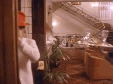 a woman in a bathrobe is standing in a room with a staircase .