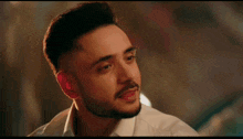 a man with a beard and a white shirt is looking at another man