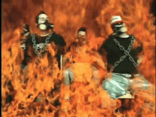 a group of people are standing in front of a fire with chains around their necks .