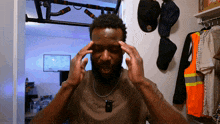 a man holds his hands to his forehead in a room