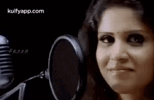a woman is smiling in front of a microphone and looking at the camera .